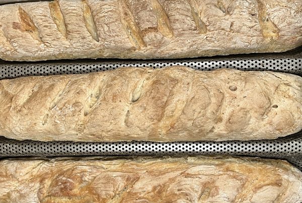 Three homemade same-day baguettes in a perforated baguette pan