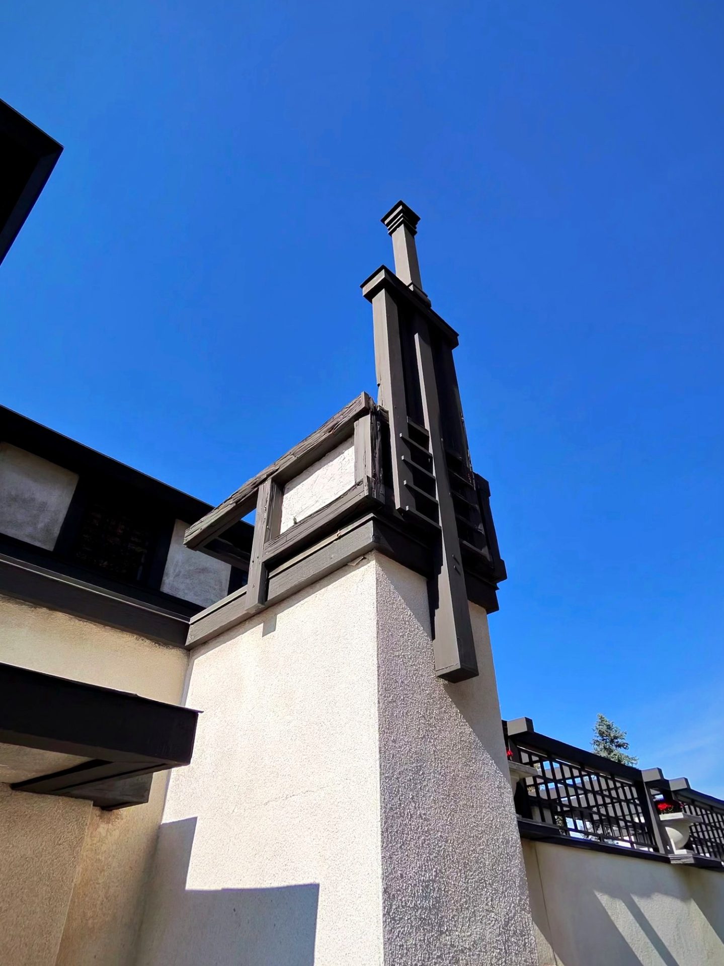 Low-angle detail of Westcott House corner with tall dark wood vertical trim and cream stucco