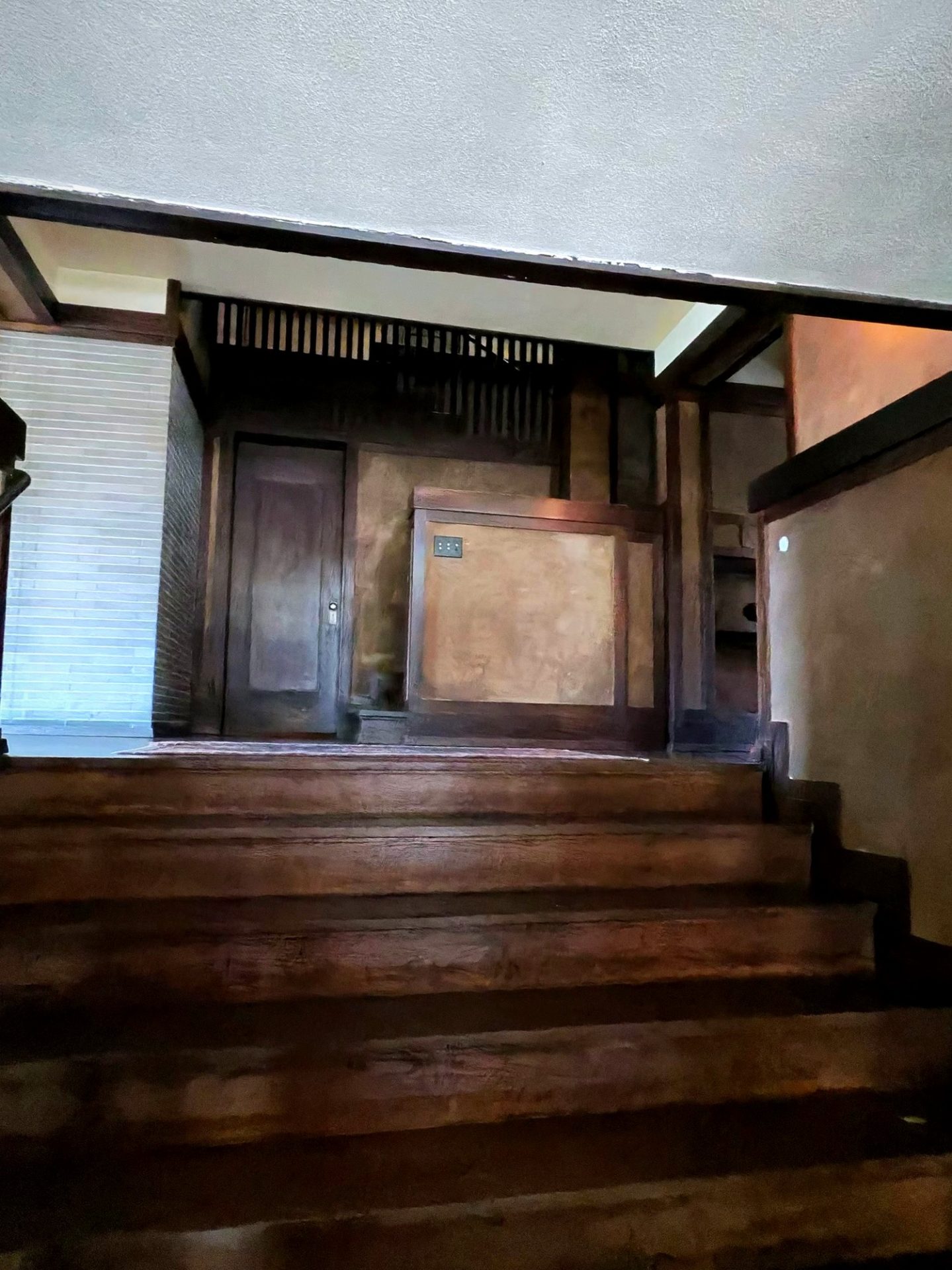 Dark wood staircase and landing with Roman brick and wooden grille at Westcott House