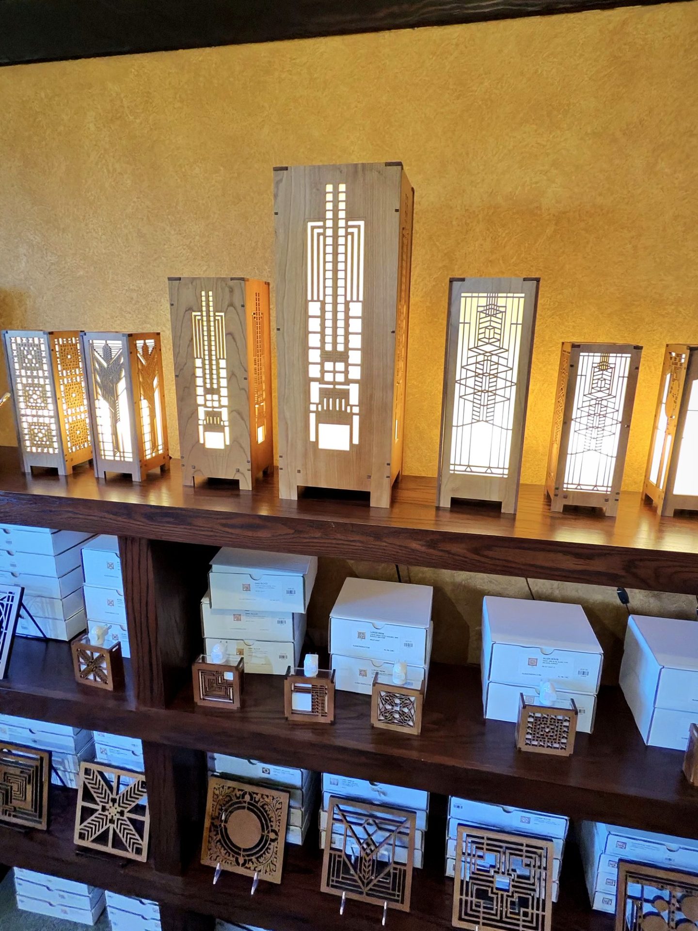 Lit wooden mission-style geometric lamps on a shelf at the Westcott House gift shop