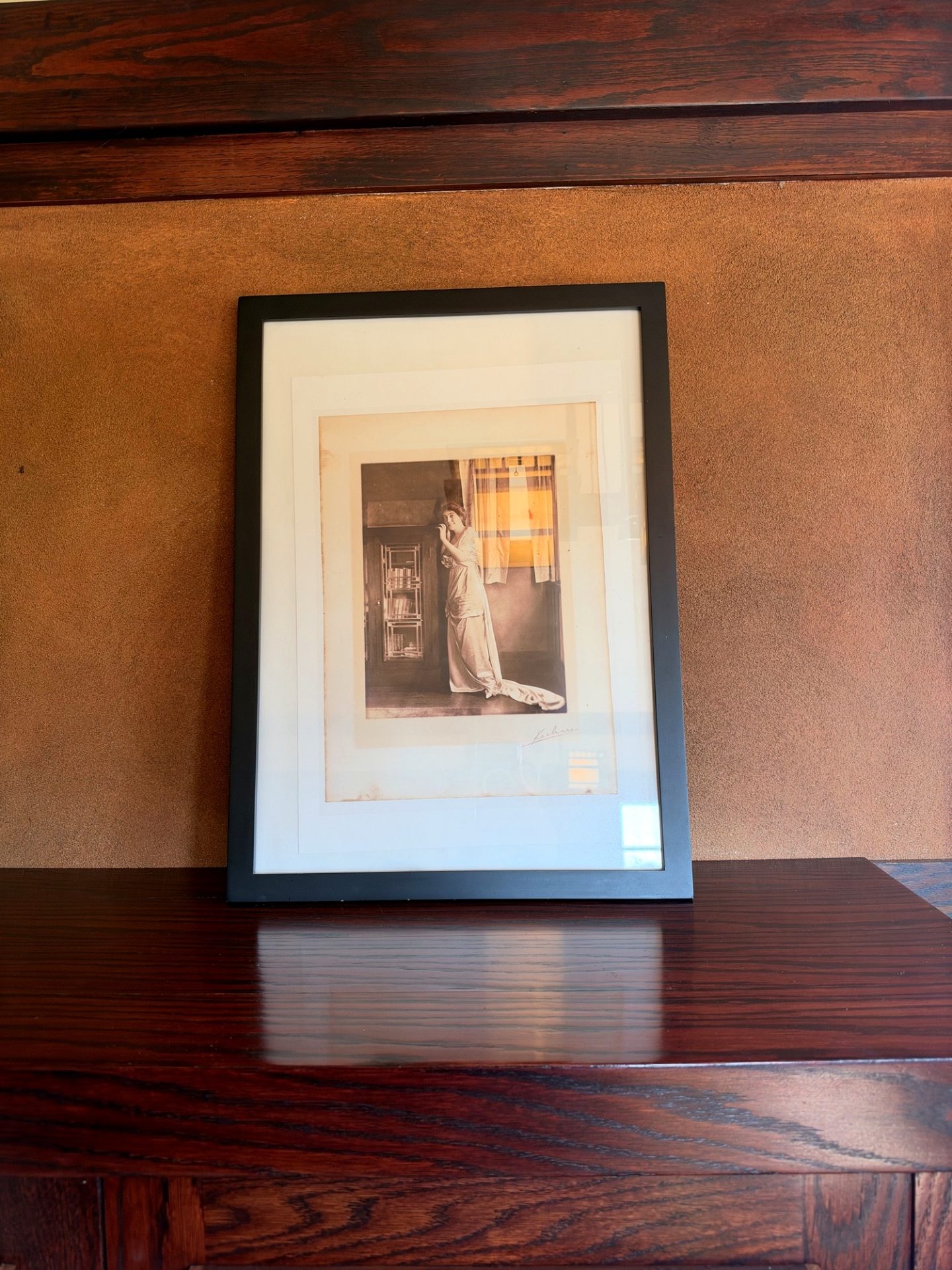 Framed historic photograph of a woman in a long white dress displayed on wood at Westcott House