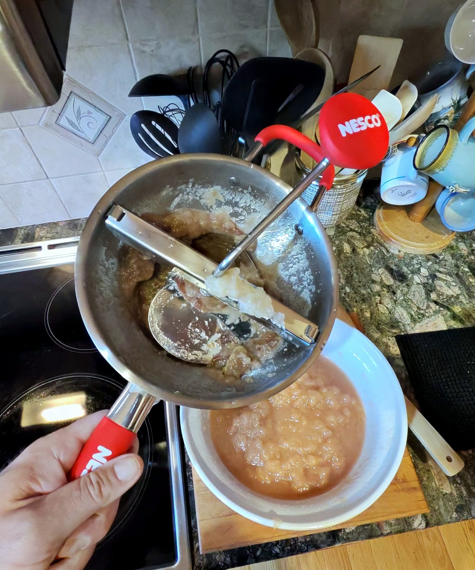 Turning the food mill to press apple pulp into a bowl