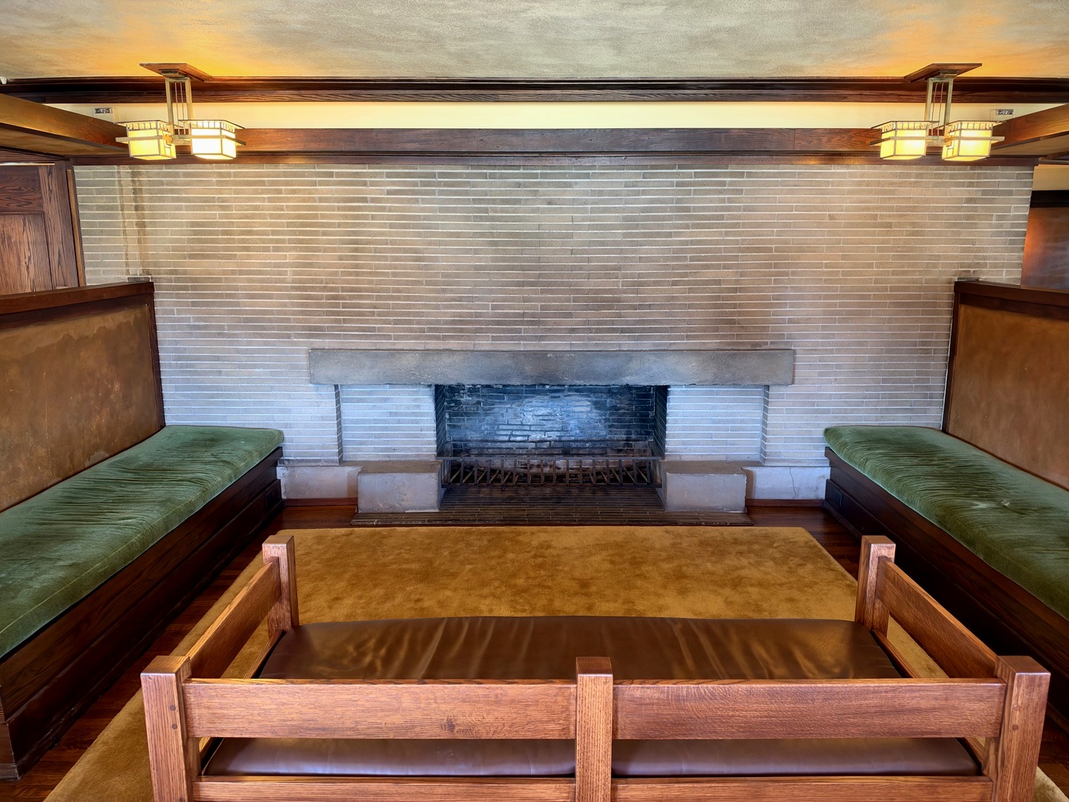 Fireplace inglenook with Roman brick, built-in green benches, and square glass lantern fixtures