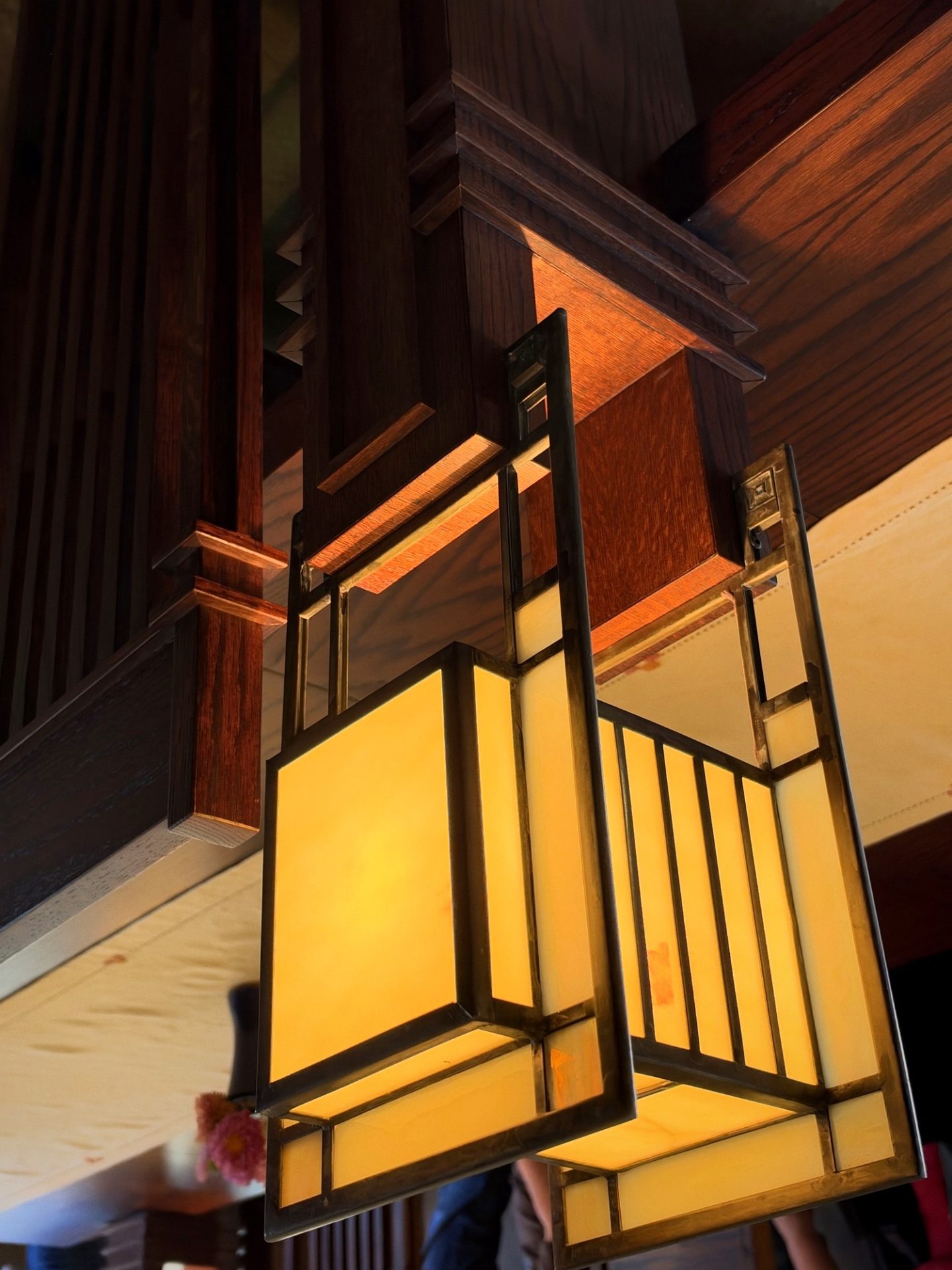 Close-up of geometric amber art-glass pendant light on dark oak beams at Westcott House