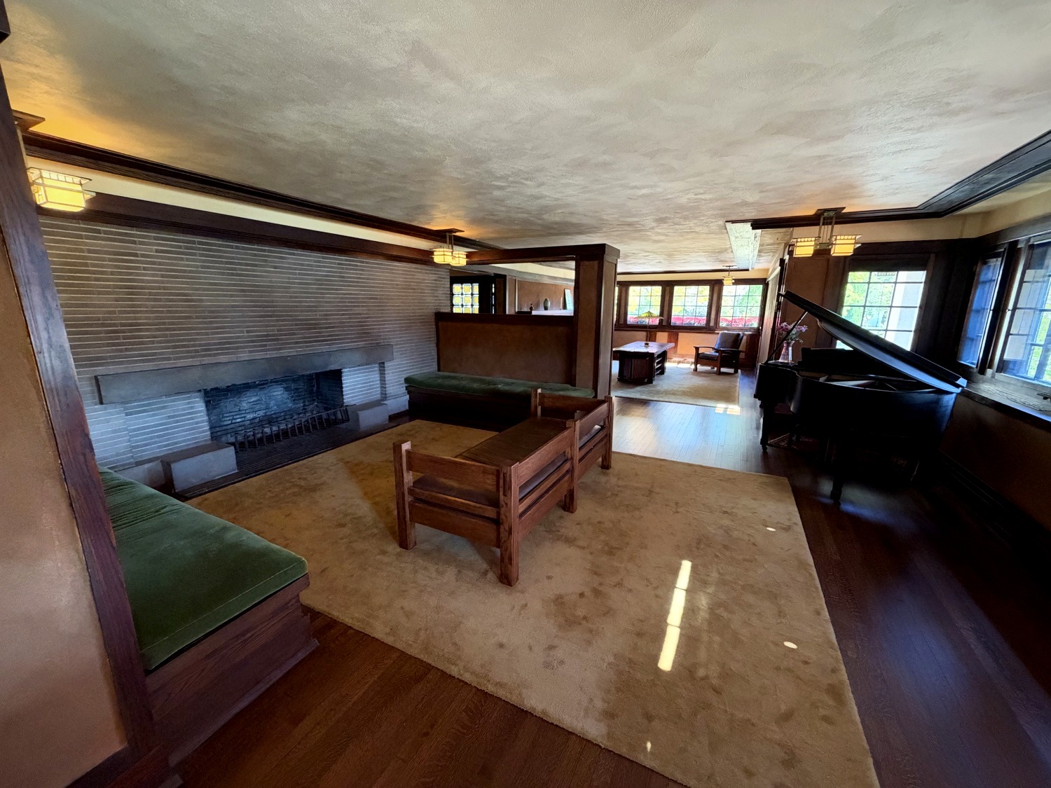 Open living room at Westcott House with Roman brick fireplace, grand piano, and Mission furniture