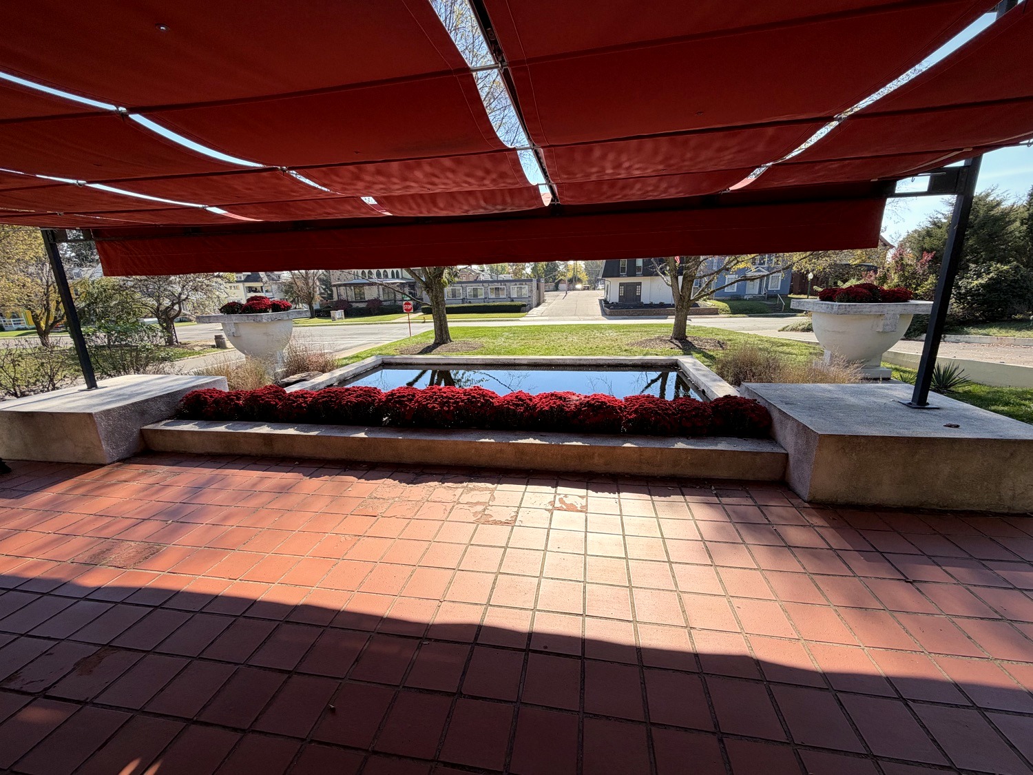 View from Westcott House terrace under red awning toward reflecting pool, lawn, and street