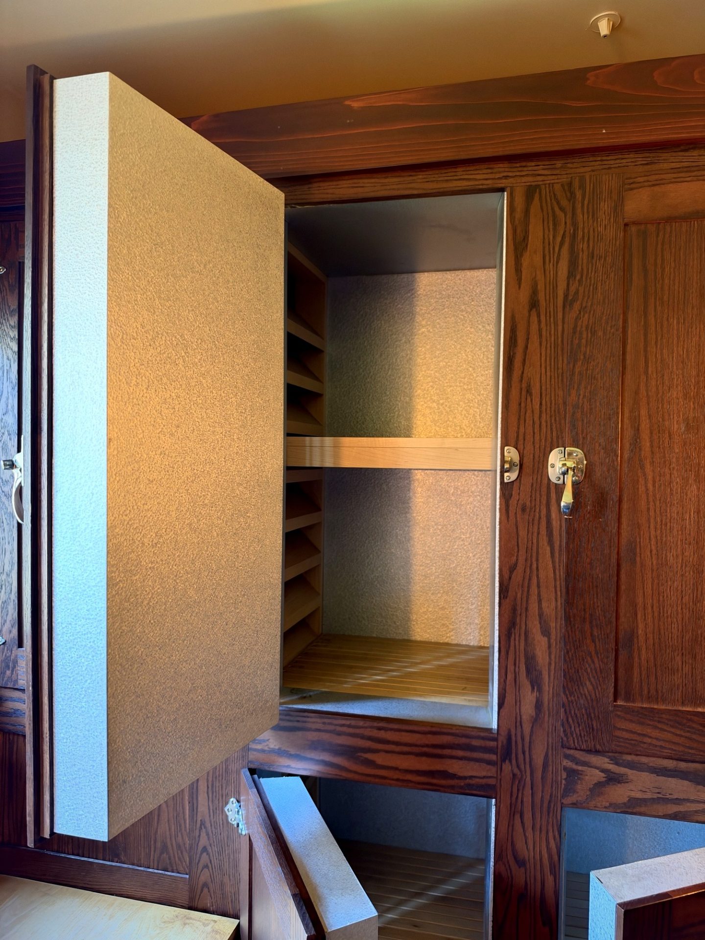 Open built-in wood-framed refrigerator with brass hardware in Westcott House kitchen cabinets