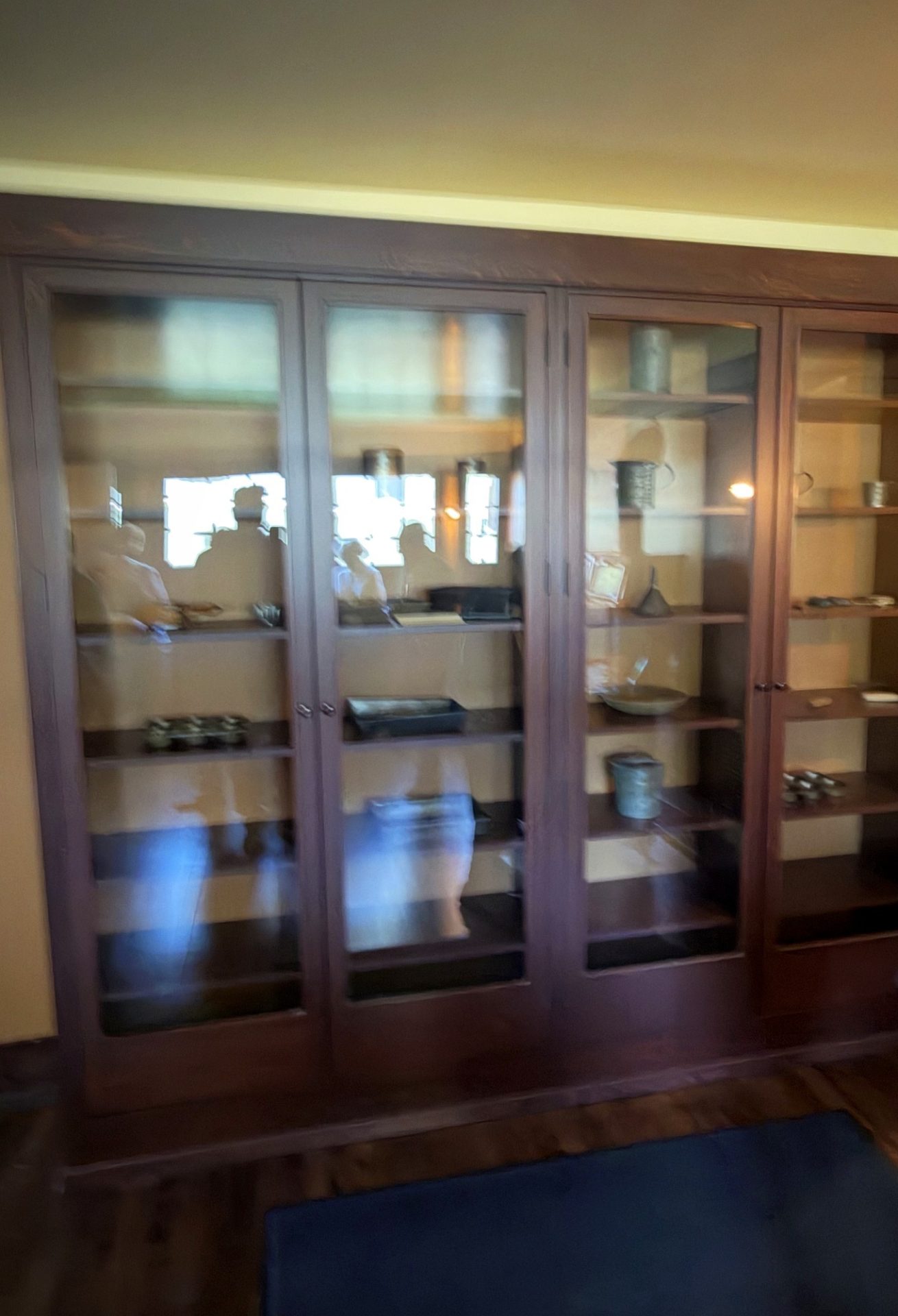 Tall dark wood glass-front pantry cabinets with period kitchenware at Westcott House