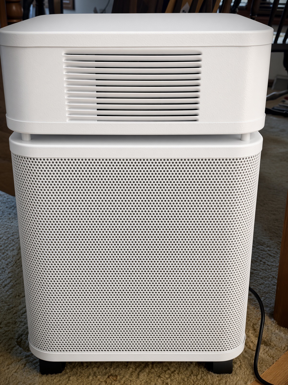 Side view of a white Austin Air HealthMate air purifier showing its louvered top vents and perforated metal body