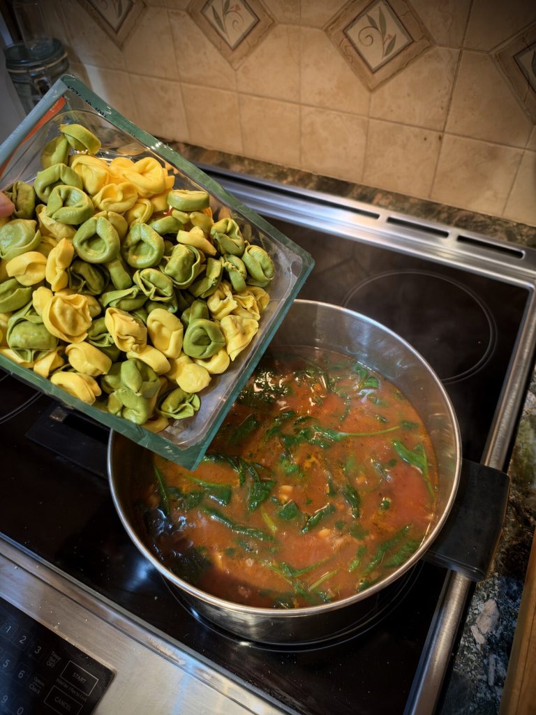Cheese tortellini simmering in the tomato broth