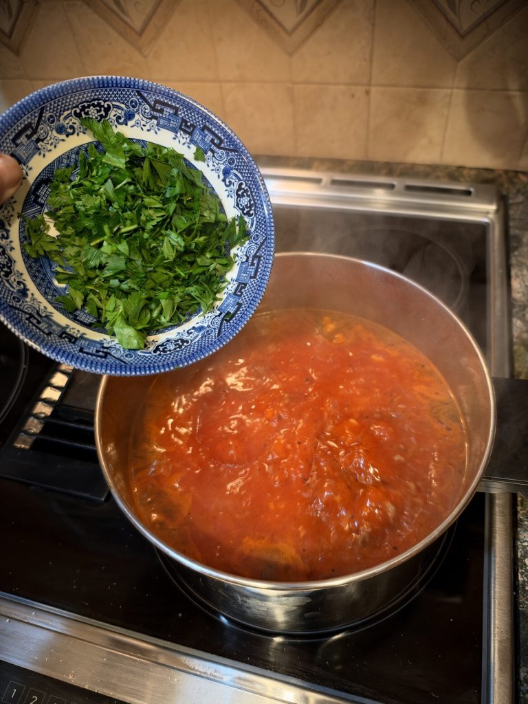 Fresh herbs going into the red tomato broth