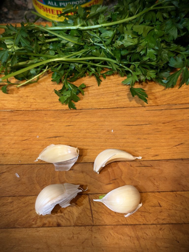 Fresh parsley and garlic cloves on a cutting board