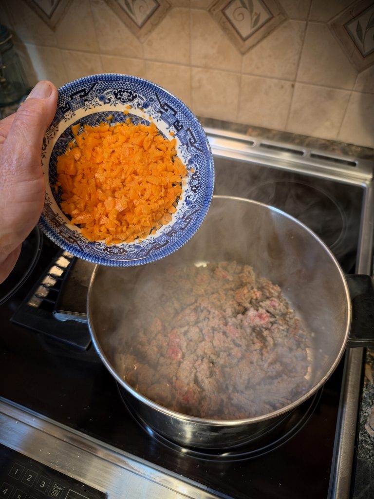 Diced carrots added to the pot with the sausage and onion