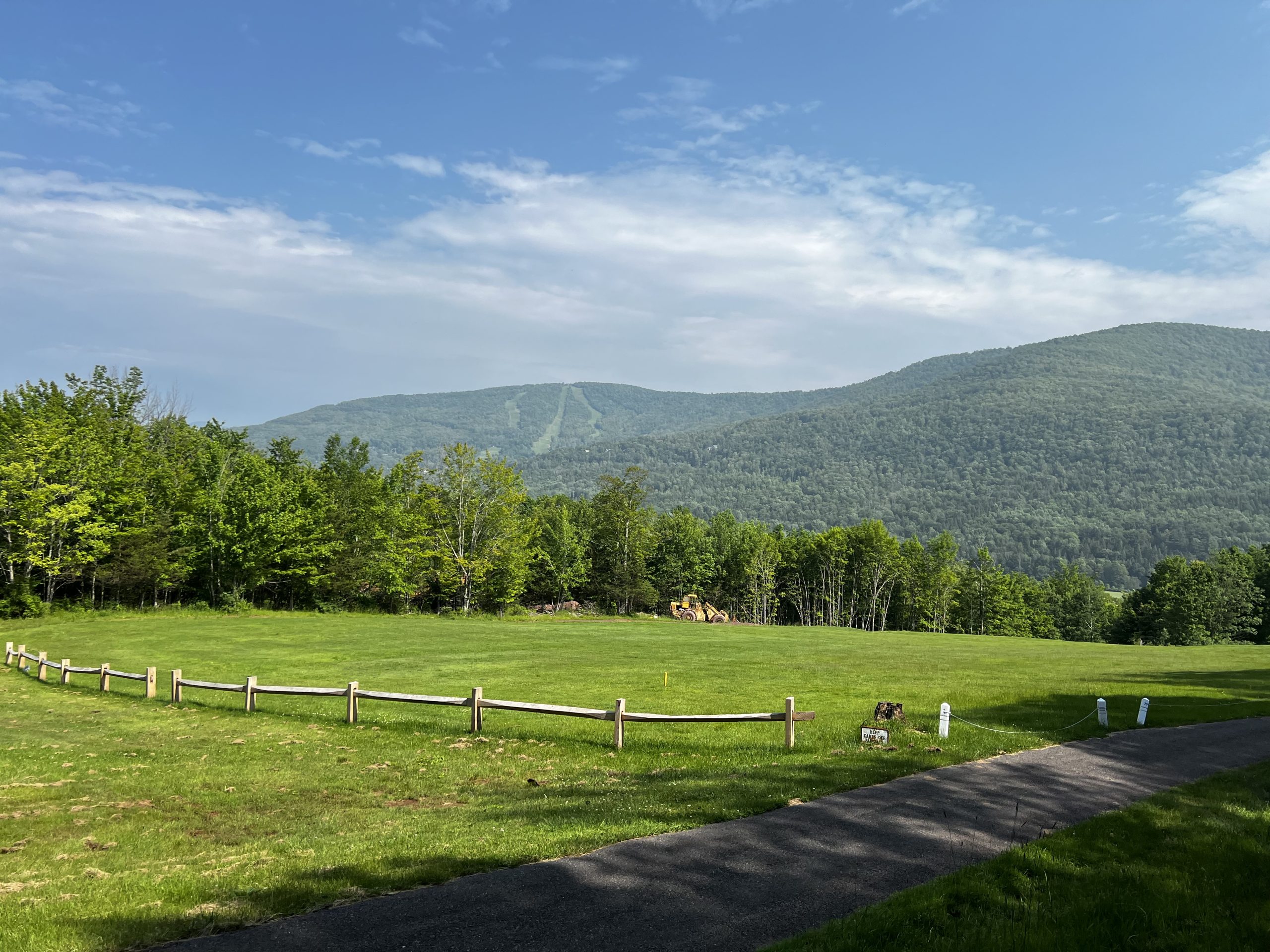Green pasture with a split-rail fence and the Catskill Mountains under a blue sky in Windham, NY