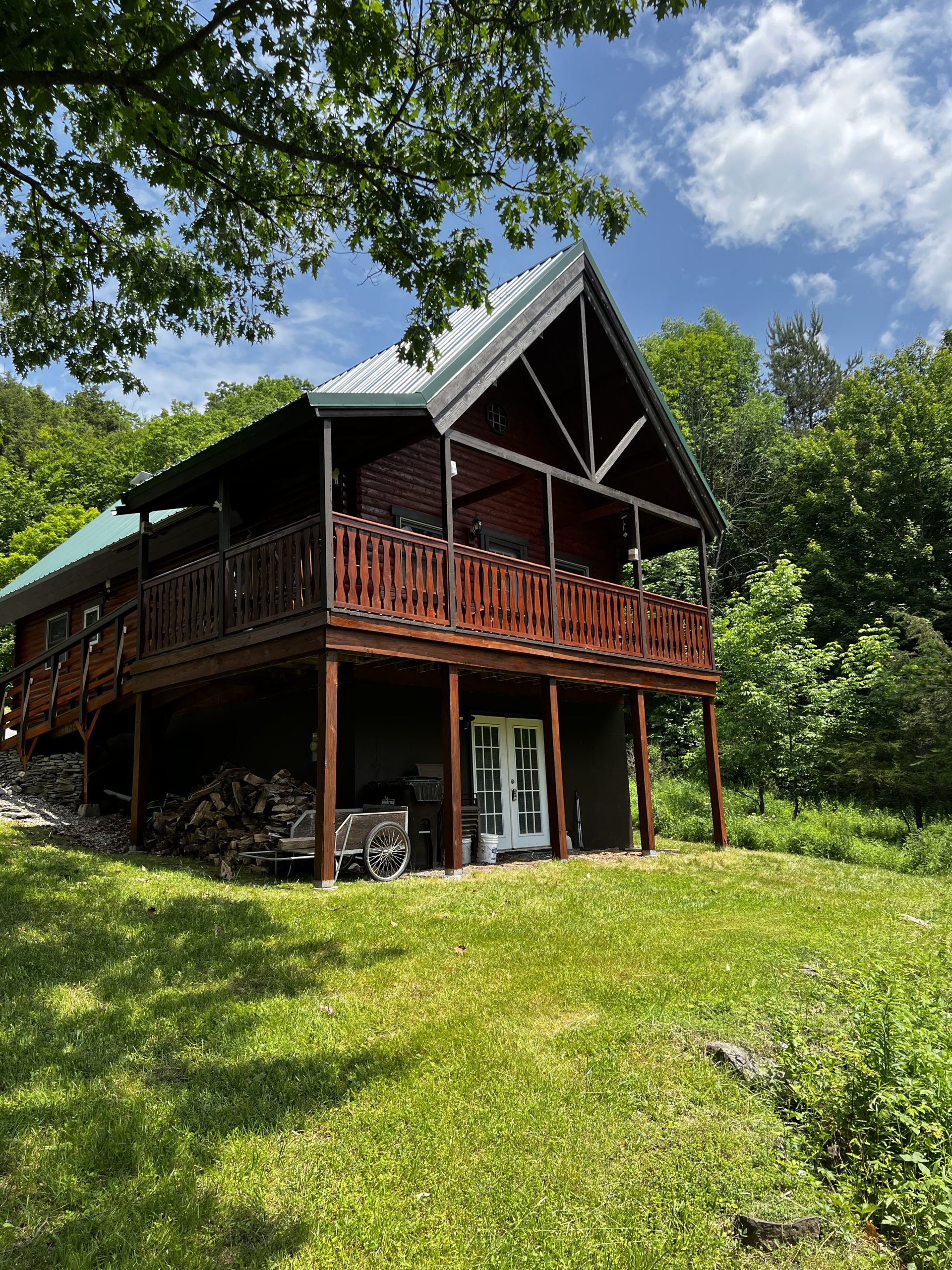 Pap Steve's red log cabin with a wraparound deck in Windham, NY, surrounded by summer greenery