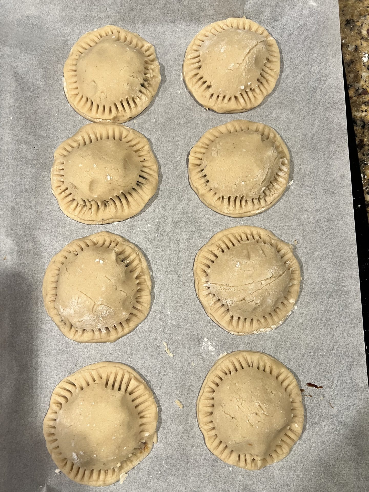 Filled and crimped raisin cookies on parchment before baking
