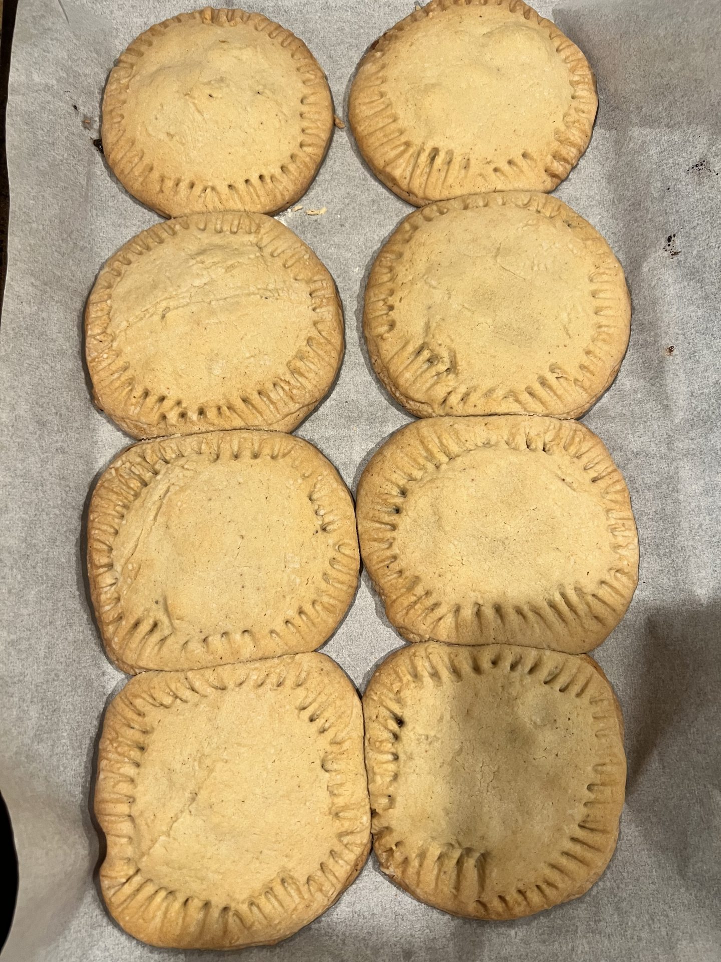 Baked raisin-filled sugar cookies cooling on parchment