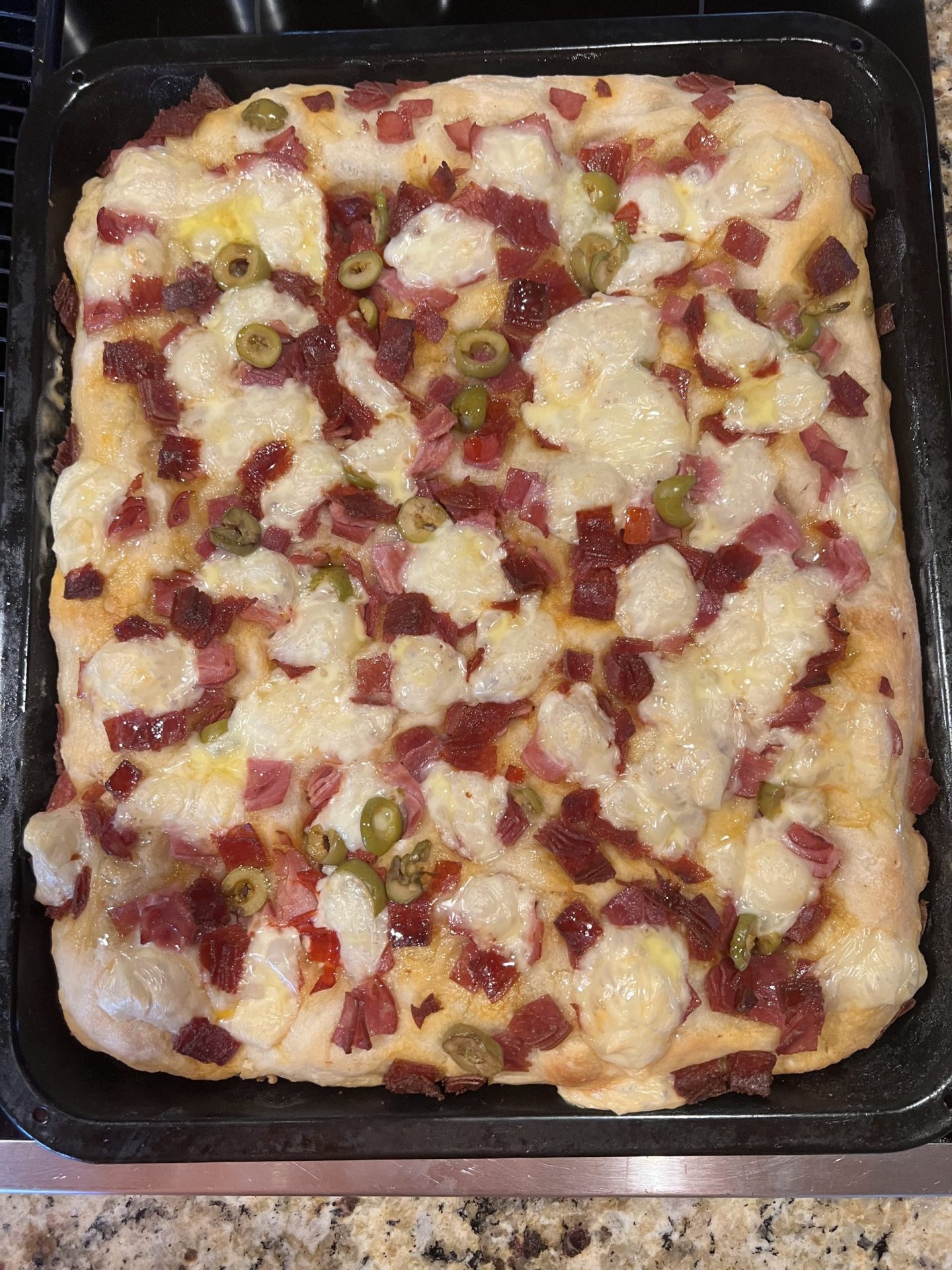 Baked Italian focaccia with meats, cheese and green olives