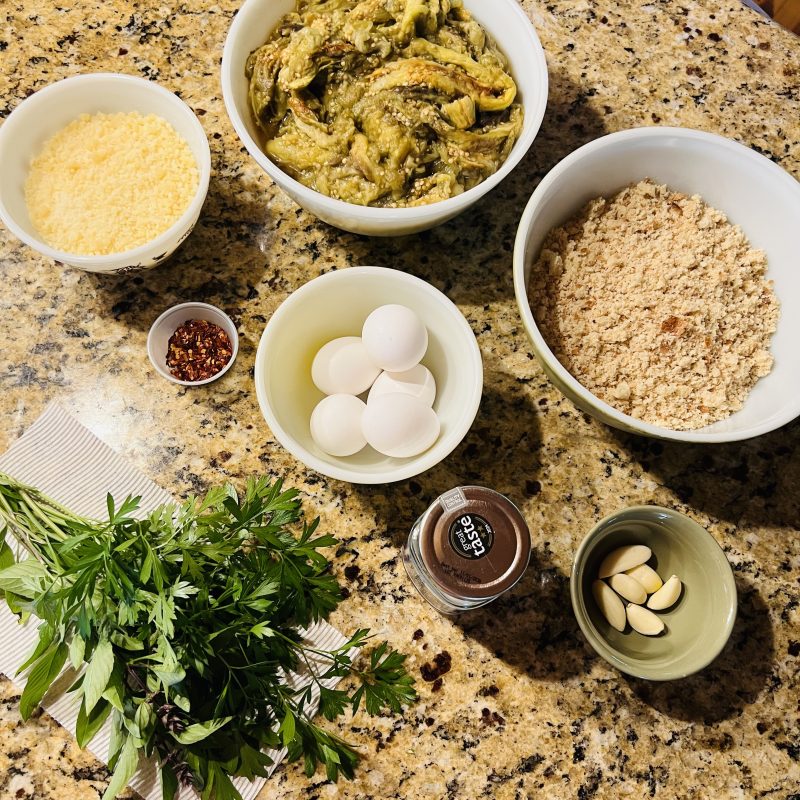 Eggplant ball ingredients laid out: eggplant, breadcrumbs, Parmesan, eggs, garlic, parsley and red pepper flakes