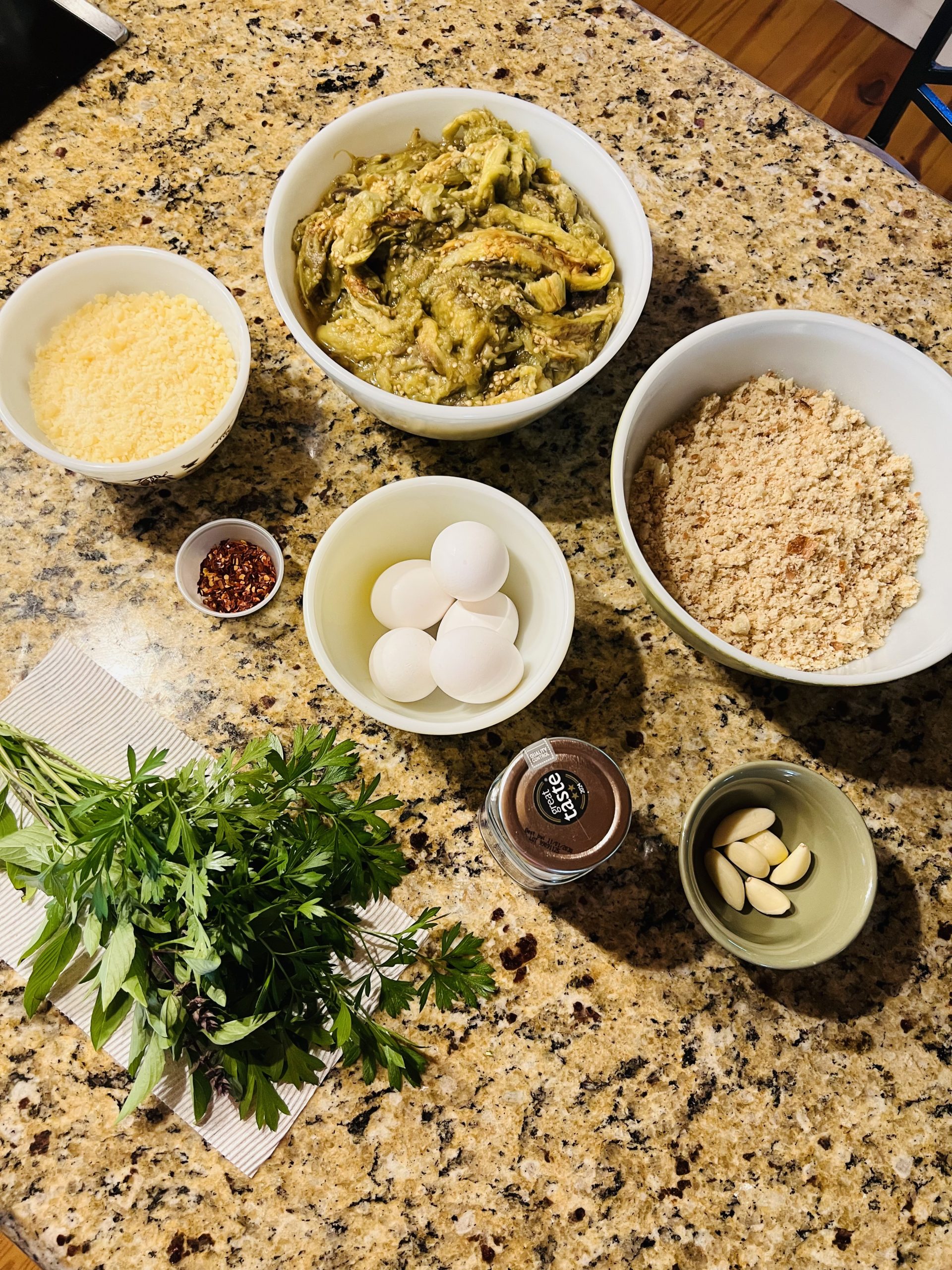 Eggplant ball ingredients laid out: eggplant, breadcrumbs, Parmesan, eggs, garlic, parsley and red pepper flakes