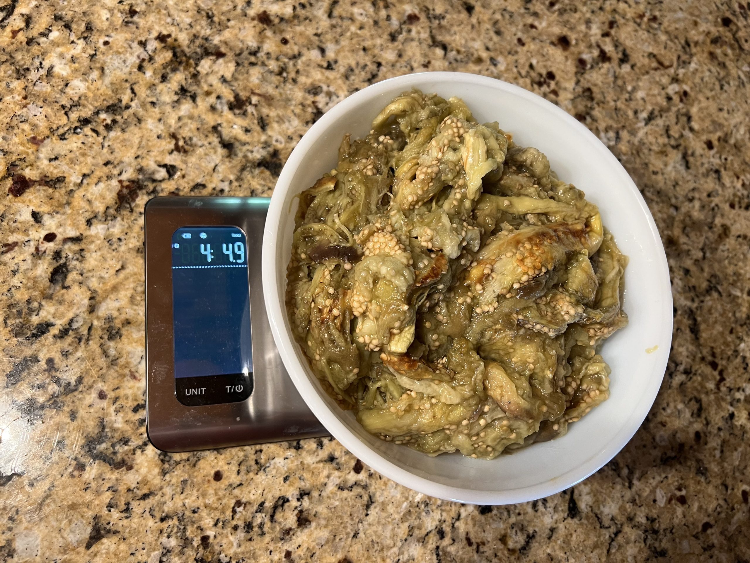 Bowl of roasted eggplant flesh on a kitchen scale reading just over 4 pounds