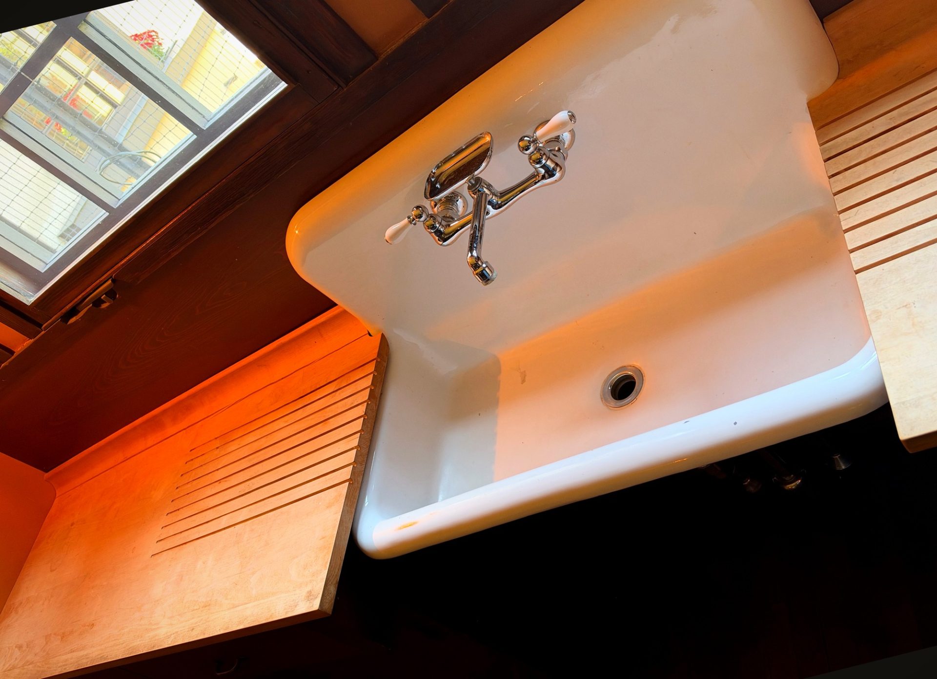 White porcelain kitchen sink with bridge faucet and wooden drainboards at Westcott House